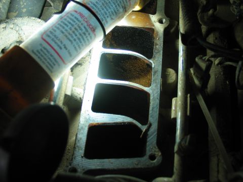 1995 Ford Bronco - Intake manifold ports show significant carbon buildup, illuminated by a flashlight.