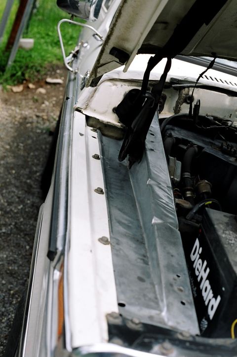 1979 Ford Bronco - Engine bay detail of a white vehicle with the hood propped open.