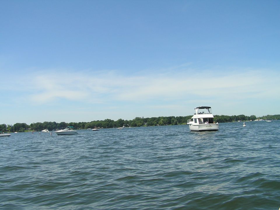 White cabin cruiser boat with black canopy on open water under clear blue sky