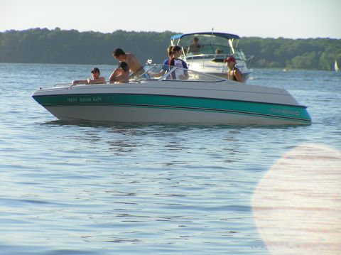 1997 Crownline 266 CCR - A white and teal boat with "FOUR WINNS" visible on its side is on the water with people aboard, while another boat is in the background.