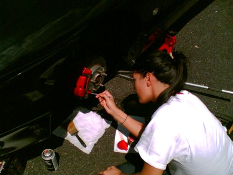 1997 Ford Probe - A person is shown painting the brake caliper of a vehicle red with a brush.