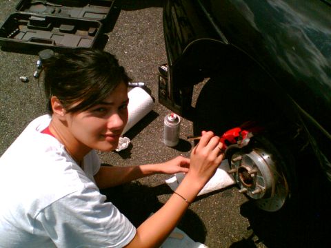 1997 Ford Probe - A woman is shown painting a car's brake caliper red, with a toolbox and spray paint can visible.