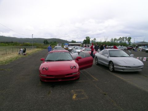1993 Ford Probe - Two Ford Probes are parked at an outdoor event with other vehicles and people in the background.