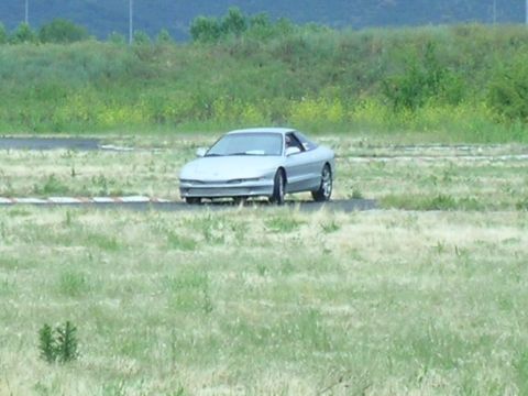 1993 Ford Probe - A silver 1993 Ford Probe is seen on a track with grassy surroundings.