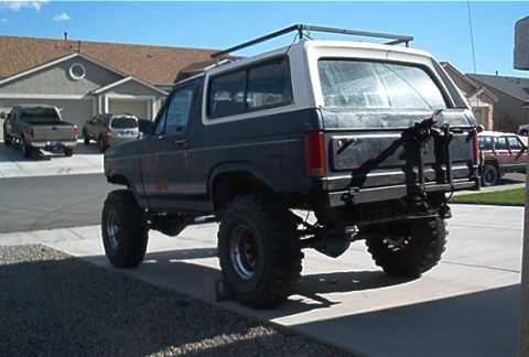 1986 Ford Bronco - This lifted 1986 Ford Bronco is parked in a suburban driveway with other vehicles visible.