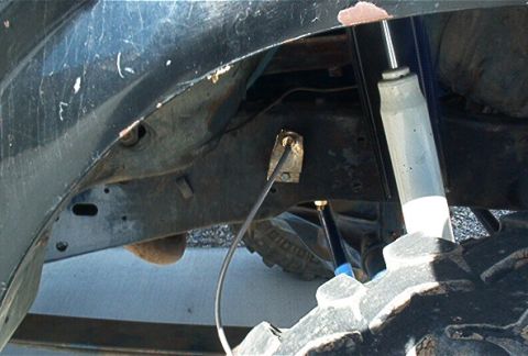 1986 Ford Bronco - The underside of a vehicle shows a shock absorber and part of the tire, with visible wear and tear.