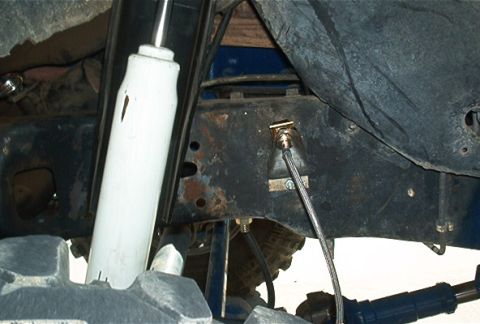 1986 Ford Bronco - Undercarriage view of a vehicle's suspension system, showing frame and brake lines.