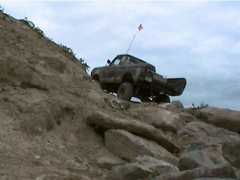 1977 Ford F-150 - A truck navigates a steep, rocky terrain under a cloudy sky.