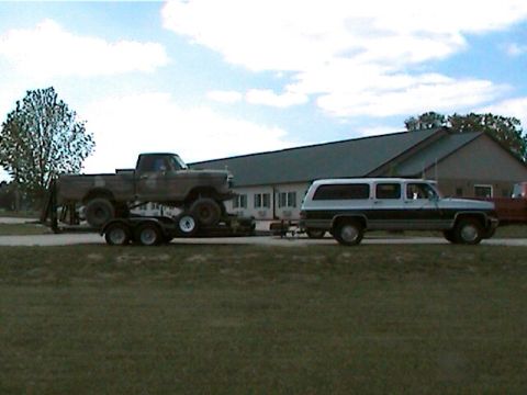 1977 Ford F-150 - A brown pickup truck is transported on a trailer pulled by a two-tone SUV.