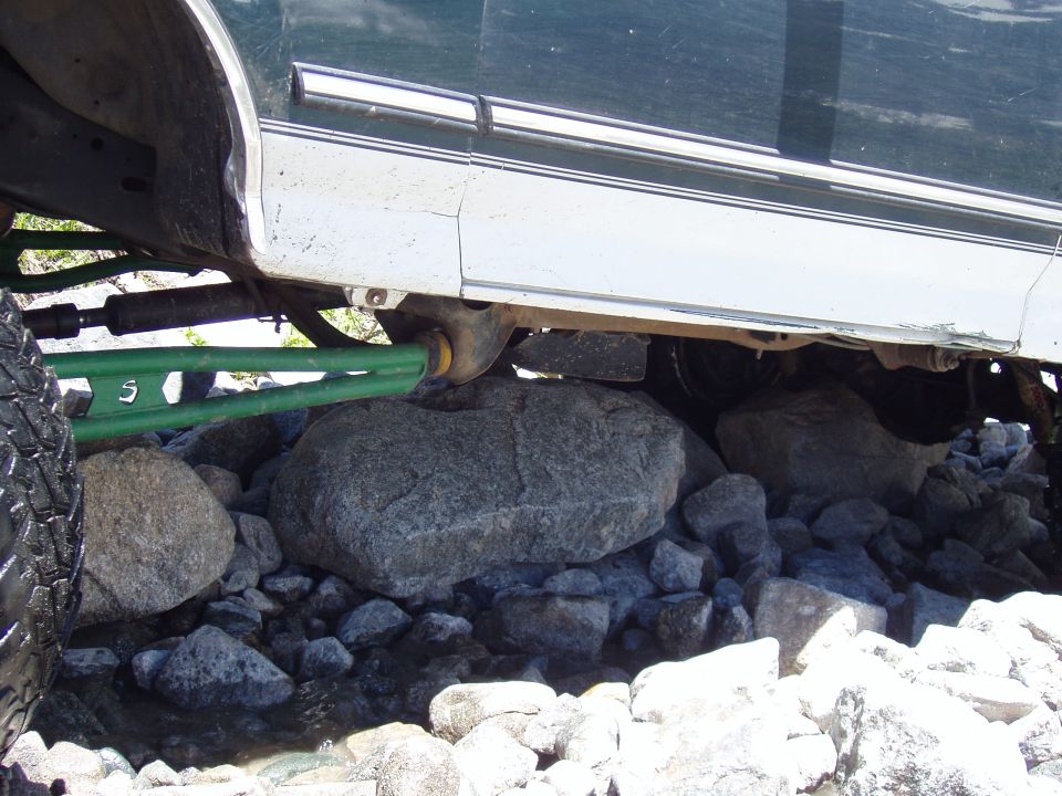 Off-road vehicle's green suspension components and undercarriage resting on rocks