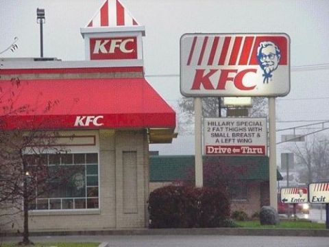 1990 Ford Bronco - KFC restaurant with its red signage shows a marquee printed with a satirical 'Hillary Special' joke above the drive-thru sign.
