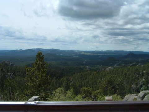 1992 Ford Probe - A wide view of rolling, tree-covered mountains under a dramatic, cloudy sky, with a guardrail in the foreground.