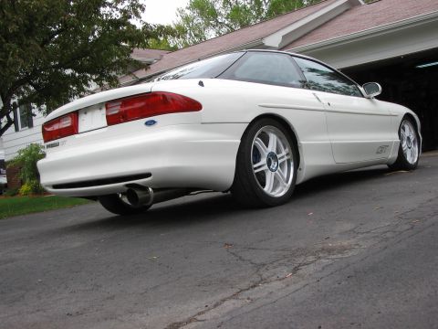 1993 Ford Probe - A white Ford Probe GT is shown from the rear quarter angle, parked in a driveway with a garage in the background.