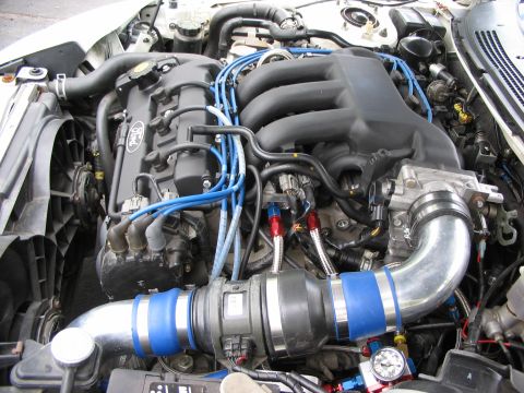 1993 Ford Probe - Close-up of a Ford engine bay, blue spark plug wires and a custom intake system.