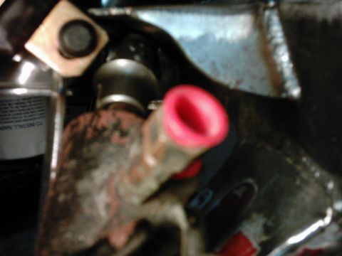 1978 Ford Bronco - A close-up view of an engine component, possibly a hose or tube, with a bright red cap. A bottle with visible text is also in the frame.