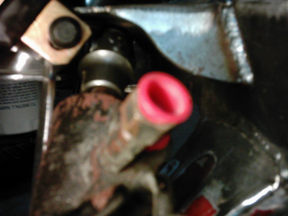 Close-up of an engine part with a red cap and a bottle with text