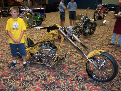 1999 Jeep TJ - A young boy stands next to a custom chopper motorcycle with flame graphics at an indoor event.
