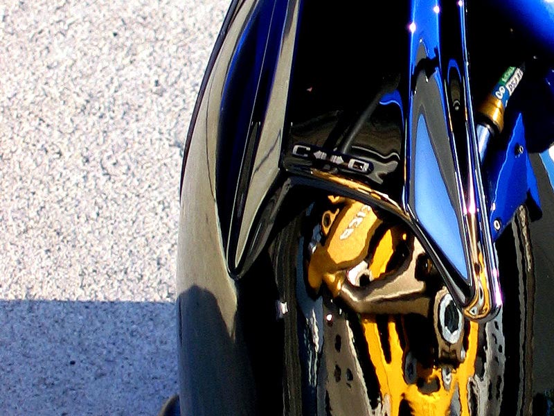 Close-up of black front fender, gold brake caliper and fork on a sport motorcycle