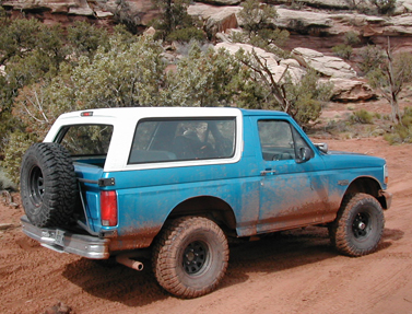 1994 Ford Bronco - This 1994 Ford Bronco is shown off-road, a blue body with a white removable top and a spare tire mounted on the rear.