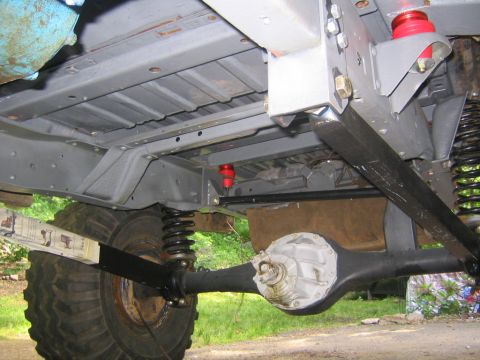 1978 Ford Bronco - Underside view of a truck/SUV chassis showing a freshly painted gray frame, front solid axle with differential, coil springs, black shock a…