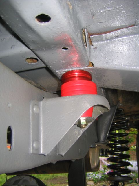 1978 Ford Bronco - Underside view of a vehicle's freshly painted gray frame showing a red polyurethane bump stop mounted above a bracket, with a yellow-zinc b…