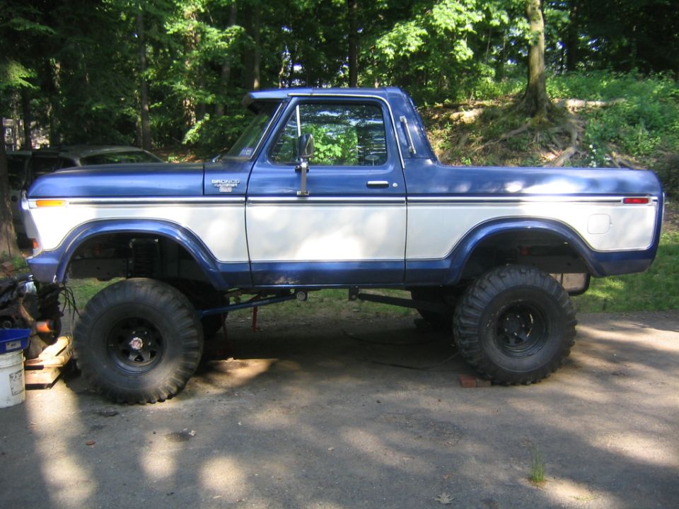 Blue and white lifted 1978 Ford Bronco in side view on big off-road tires