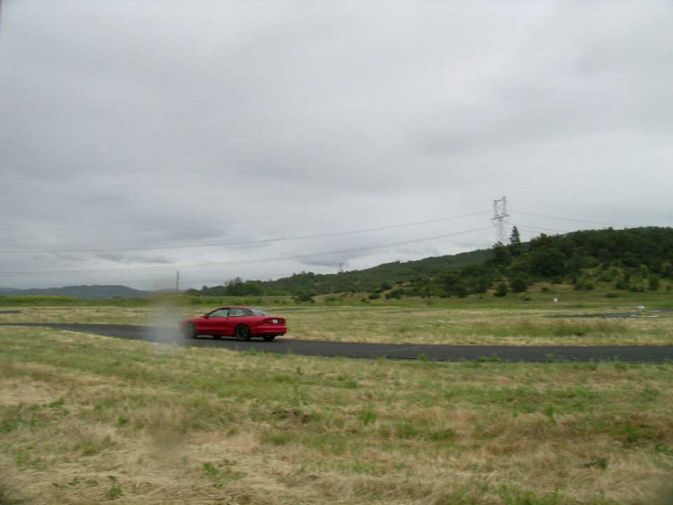 Red 1993 Ford Probe drifting on a track with smoke from tires