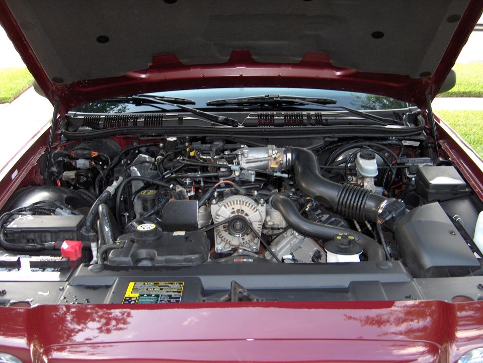 Engine bay of a maroon vehicle showing V8 with alternator and air intake tube