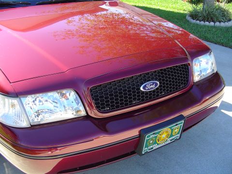 2004 Ford Crown Victoria - Close-up of the front grille and headlights of a red Ford Crown Victoria.