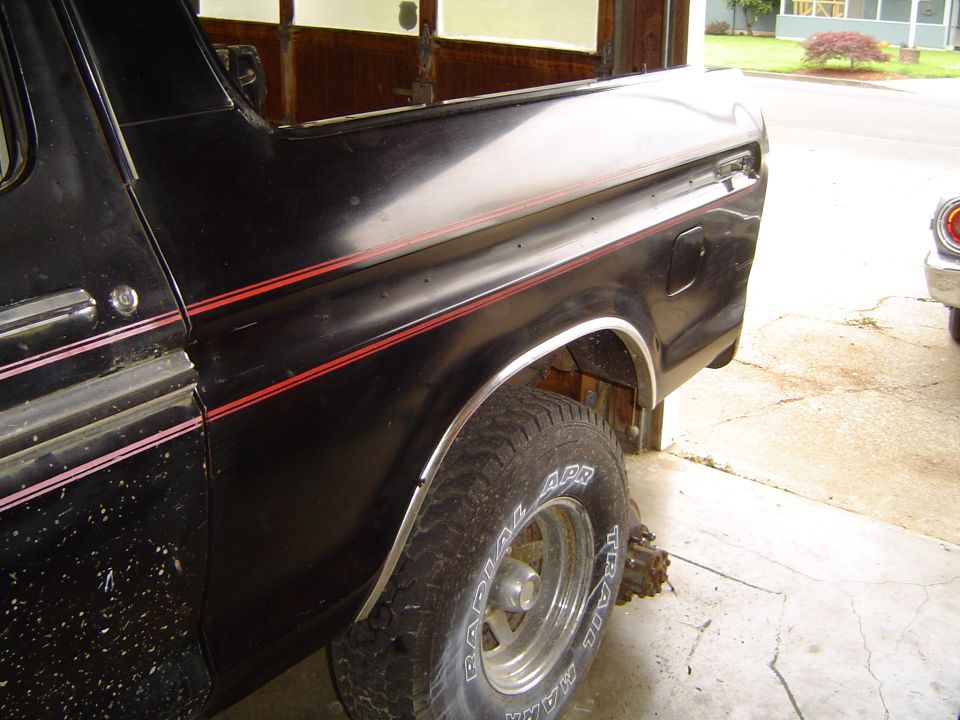 Black Ford truck rear quarter with red pinstripes, chrome fender trim and Trail Mate white-letter tire