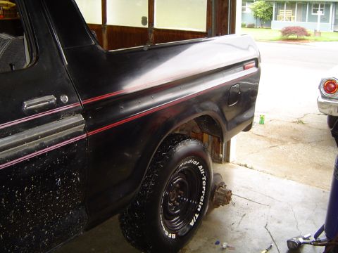 1979 Ford Bronco - Rear three-quarter view of a black square-body Ford SUV with red pinstripe side tape, the white fiberglass/painted removable hardtop rear s…