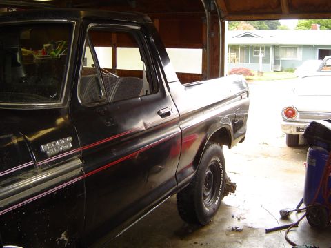 1979 Ford Bronco - Driver-side view of a black late-1970s Ford Bronco with a removable hardtop, red pinstripes and Ranger XLT badging, backed partway out of a…