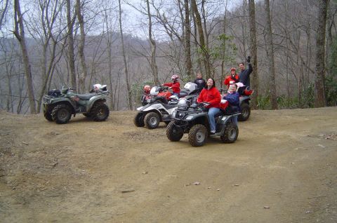 1993 Ford Bronco - Several ATVs with riders are gathered on a dirt path in a forest setting.