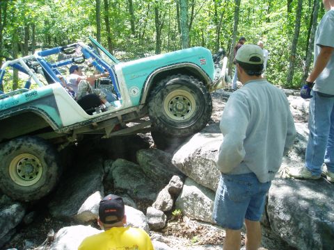 1969 Ford Bronco - A modified off-road vehicle navigates a challenging rocky terrain with spectators observing the action.