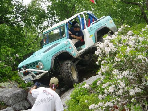 1969 Ford Bronco - 1969 Ford Bronco navigates a challenging rocky trail with assistance.