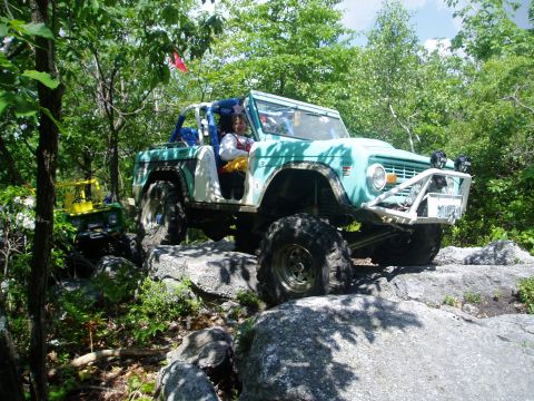 1969 Ford Bronco - This modified early Bronco is tackling a challenging rock crawl with a second vehicle in the background.