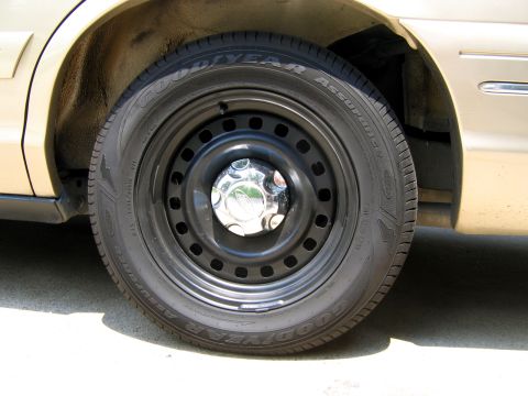 2000 Ford Crown Victoria - Close-up of a gold 2000 Ford Crown Victoria's front wheel and tire assembly.