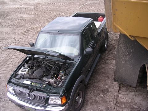 1985 Ford Bronco - Green Ford Ranger pickup truck with hood open, parked next to a large yellow construction vehicle.