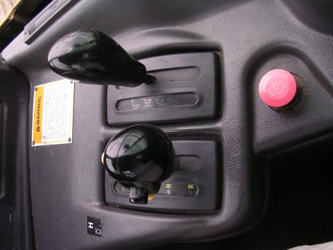 1985 Ford Bronco - The interior of a vehicle displays two gear shifters and a parking brake button, with a warning label on the dashboard.