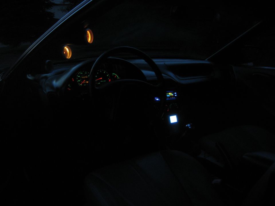 Car interior at night, showing dashboard, steering wheel, and illuminated gauges