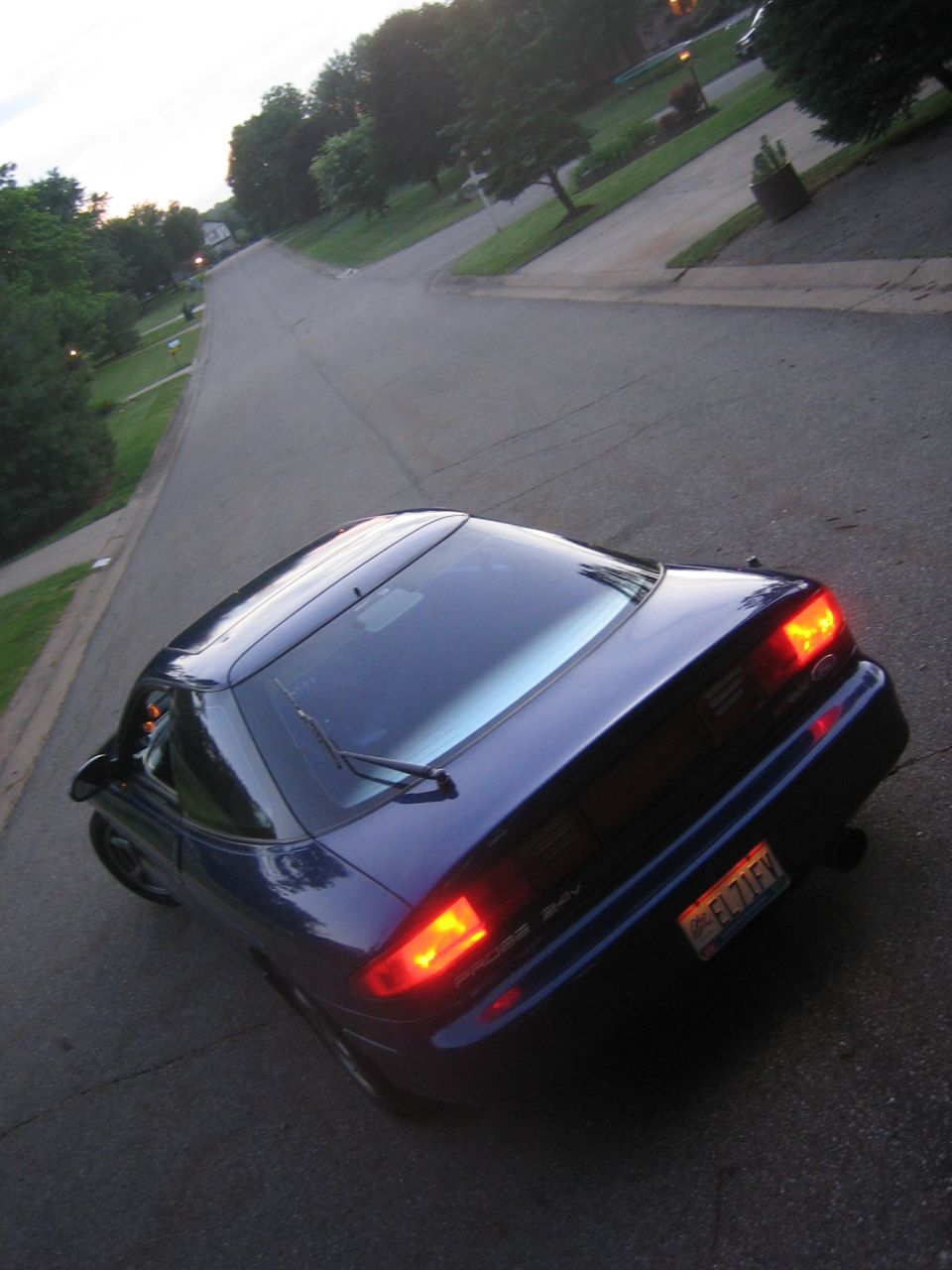 Blue 1995 Ford Probe coupe with illuminated taillights, viewed from above and behind
