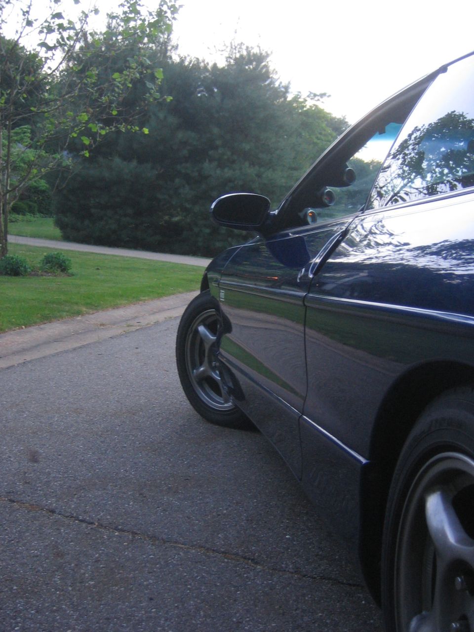 1995 Ford Probe side view, parked on asphalt street with trees in background