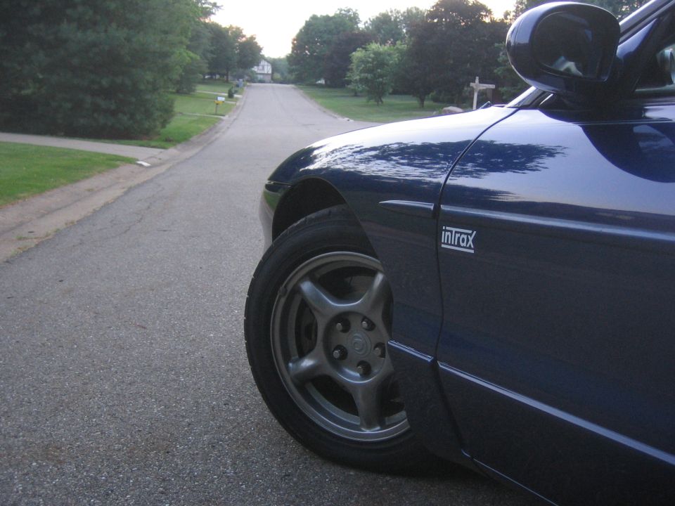 Blue car with 'Intrax' badge on the side, parked on a suburban street