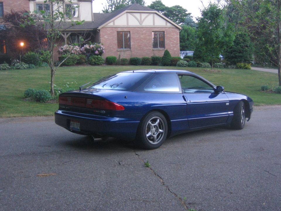 Blue 1995 Ford Probe parked on a residential street in front of a brick house