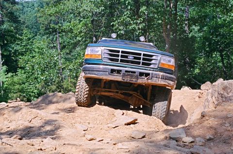 1990 Ford Bronco - Ford Bronco navigating challenging off-road terrain with steep inclines and rocks.