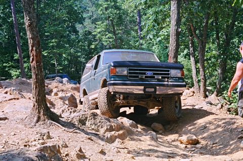 1990 Ford Bronco - A green 1990 Ford Bronco navigates a rocky off-road trail.
