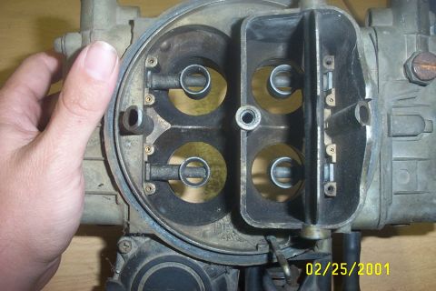 1979 Ford F-150 - A hand holds a four-barrel carburetor, showing the internal workings and throttle plates.