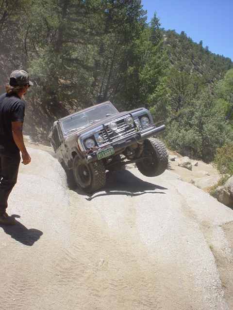 1991 Ford Bronco - An off-road vehicle navigates a challenging rocky incline on a sunny day.