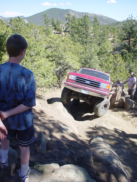 1991 Ford Bronco - This 1991 Ford Bronco is navigating a rocky off-road trail with a young spectator observing the action.