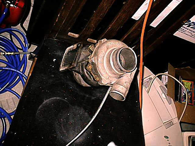 Turbocharger with blue hoses and orange cord on a black surface